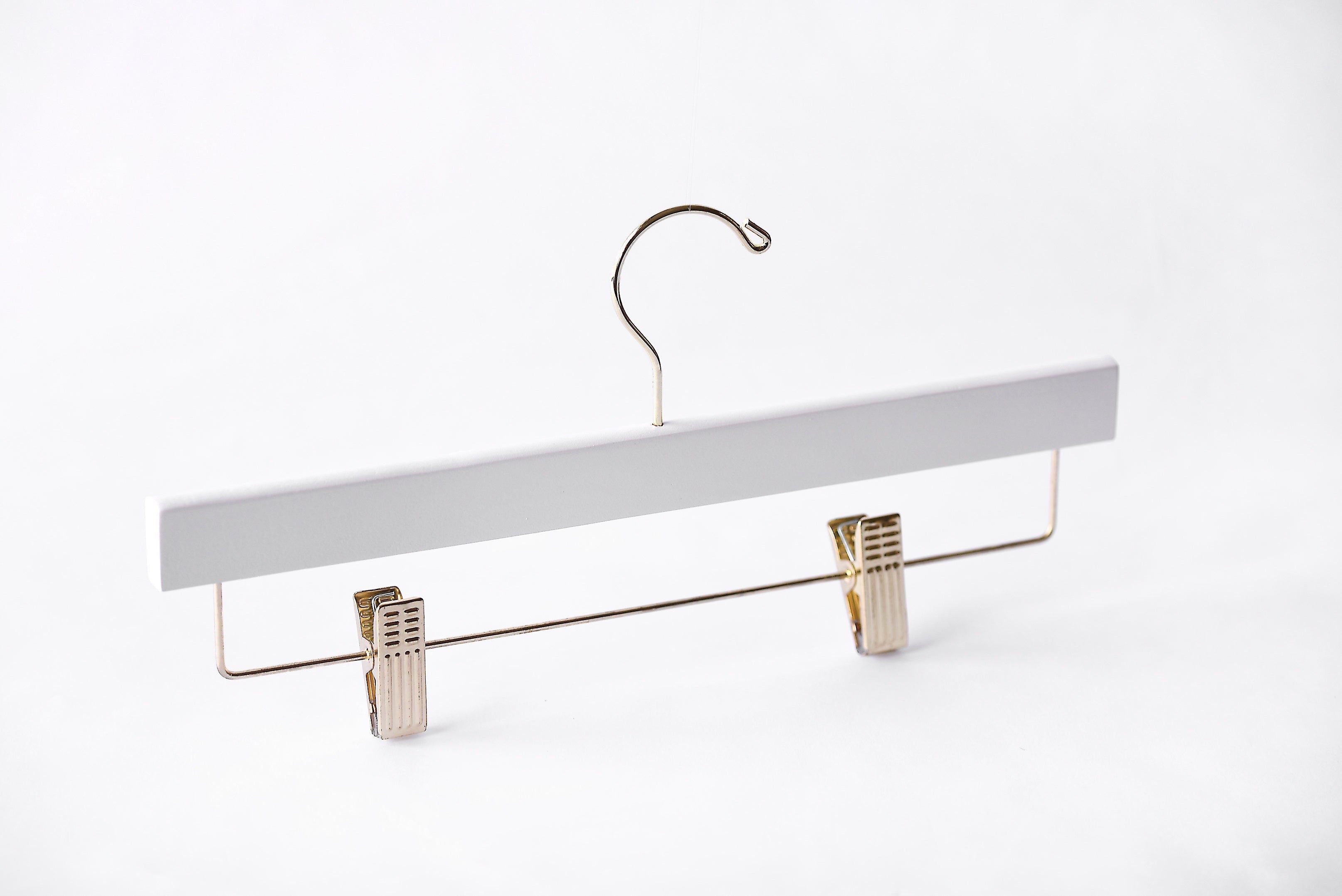White Wooden Bottom Hanger with a gold hook and adjustable cushion clips for residential closets and retail stores