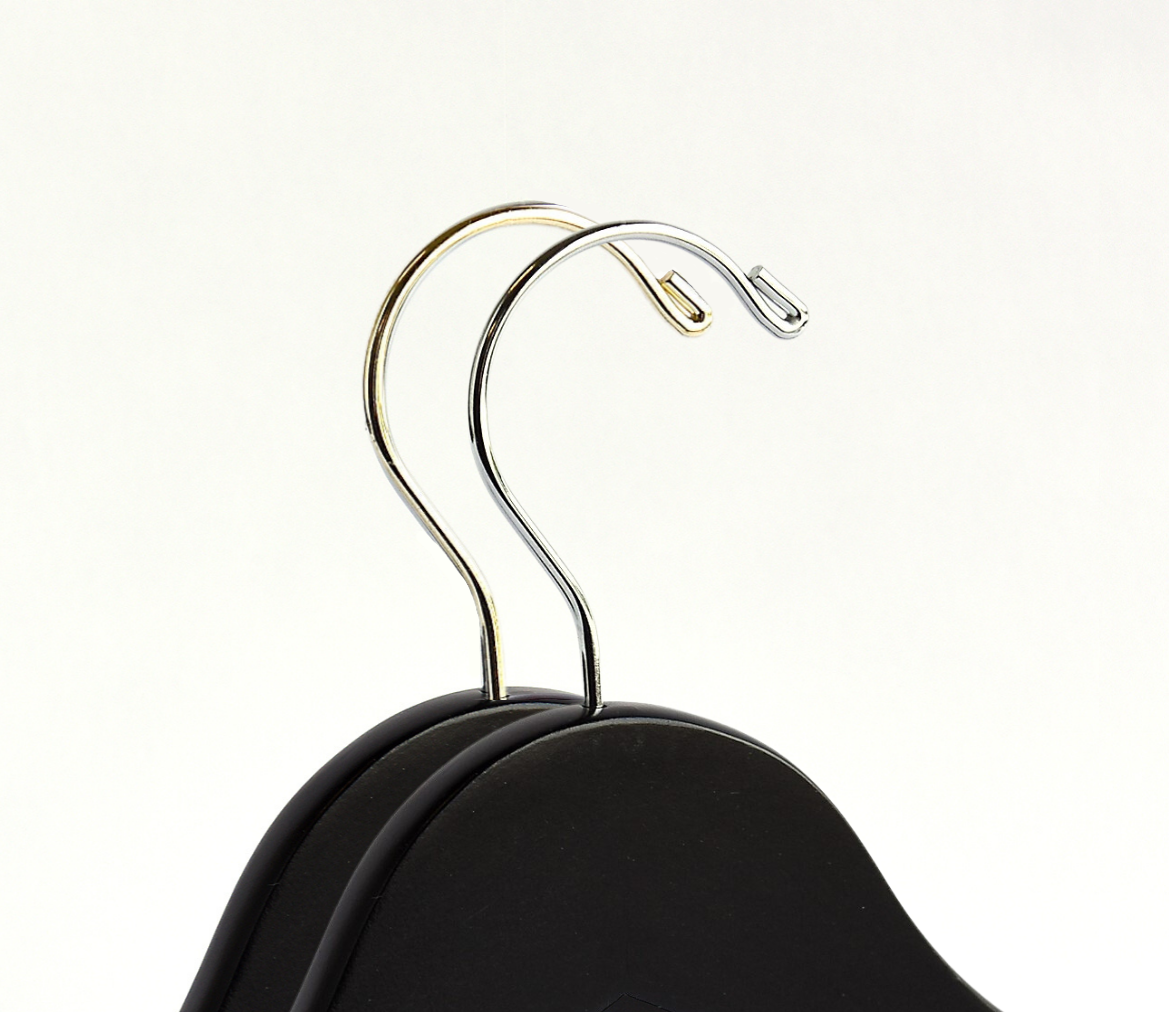 The top of two matte black wood suit hangers with a silver hooked one in front and a gold hooked one in the back