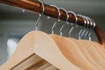Load image into Gallery viewer, Customizable Natural Maple Wooden Clothes Hangers with silver hooks hanging on a clothing rack
