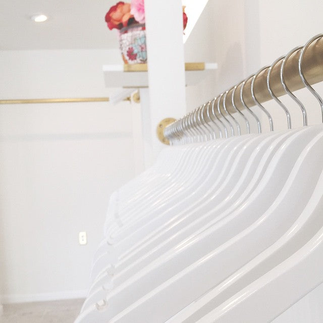 High quality White Wooden Combination Hangers with silver hooks hanging on a retail store’s clothing rack