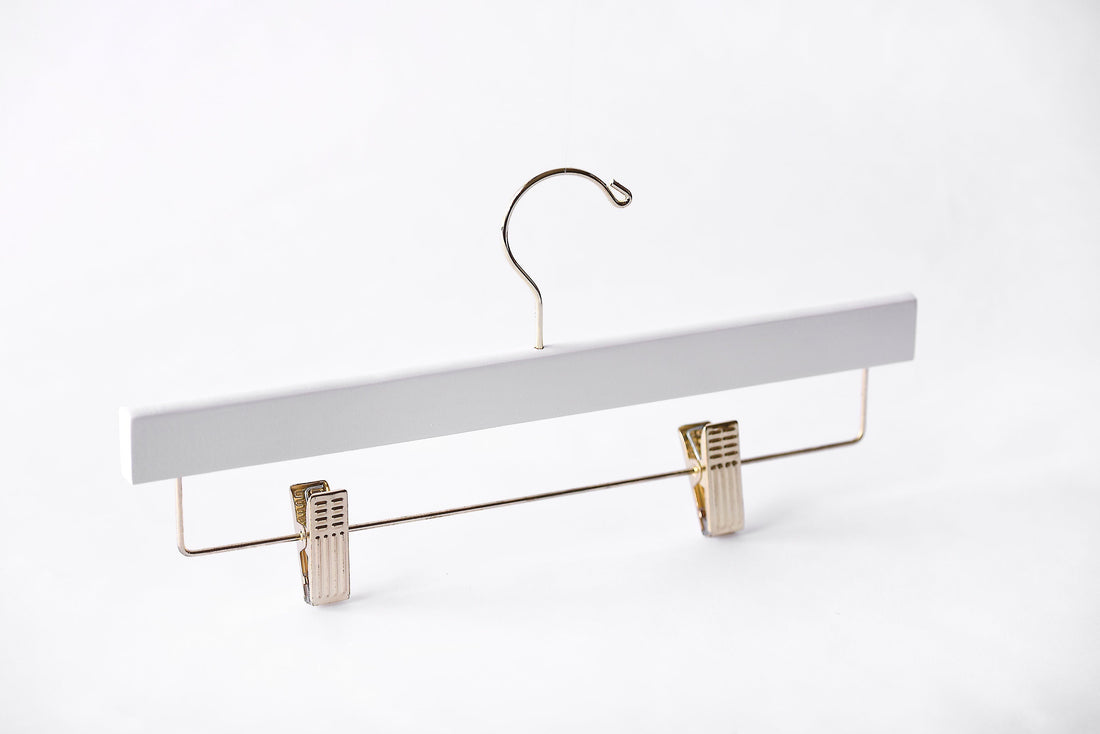 White Wooden Bottom Hanger with a gold hook and adjustable cushion clips for residential closets and retail stores