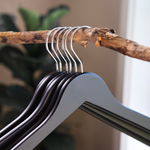 Load image into Gallery viewer, Matte Black Wooden Combination Hangers with silver hooks hanging on a branch for home closets and retail spaces
