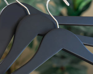 Three Matte Black Wooden Combination Hangers with silver hooks, shoulder notches, and pant bar clips for adult’s clothing