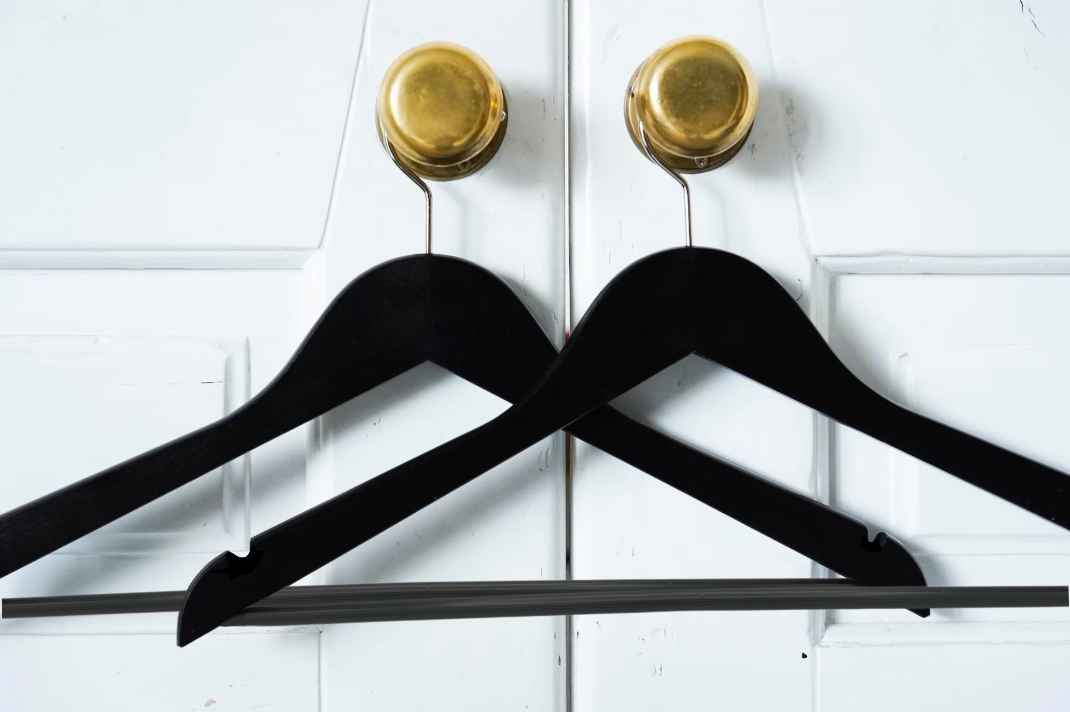 Two Matte Black Wooden Suit Hangers with pants bar for custom wedding hanger designers hanging on closet door’s doorknob #hook-color_silver-hook