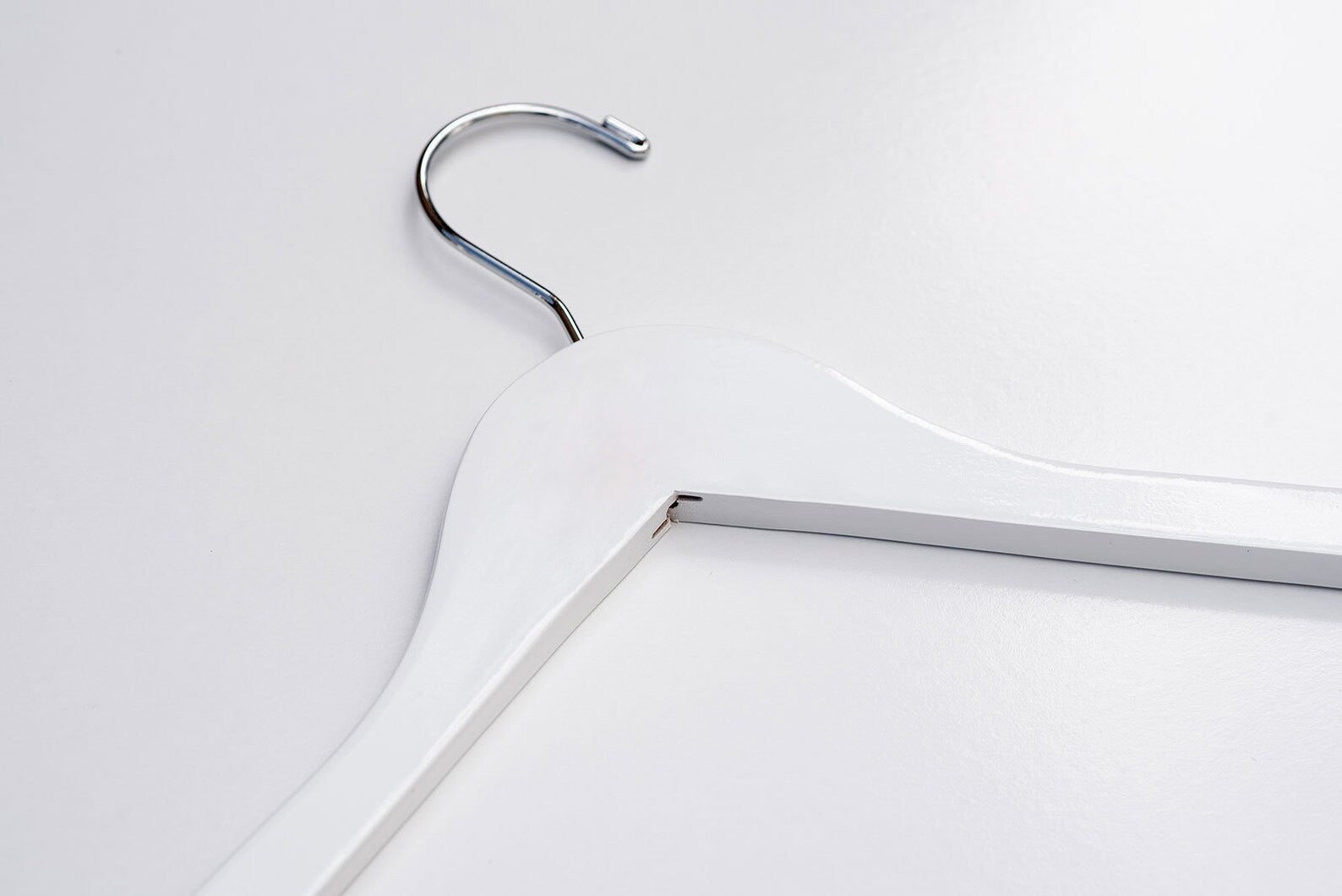 A White Wooden Clothes Hanger lying down with a silver hook for luxury closets and stores #hook-color_silver-hook