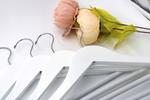 Load image into Gallery viewer, White Wood Flat Suit Hangers with silver hooks for residential closets and retail spaces lying on a table next to flowers #hook-color_silver-hook
