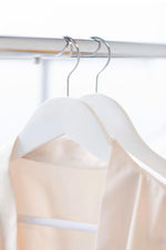 Load image into Gallery viewer, Wedding quality White Wood Suit Hangers with pant bar hanging on clothing rack with pink bridesmaid’s robes hanging on it #hook-color_silver-hook
